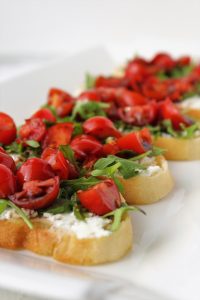 bread with goat cheese spread arugula tomatoes and balsamic on a platter