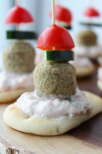 mini naan bread, topped with yogurt sauce, meatball, cucumber, tomato on a toothpick