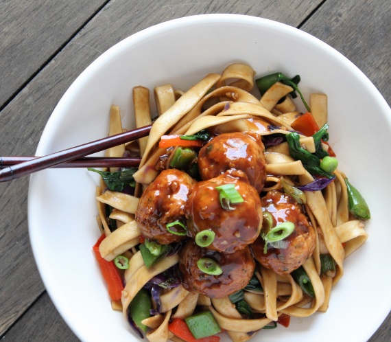 white bowl chop sticks lo mein noodles and veggies with hoisin glazed meatballs with wood backdrop
