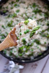 large skillet white wine risotto with peas asparagus close of photo with wooden spoon