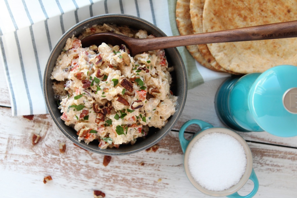 grey bowl with chicken salad and spoon pita bread and salt and pepper in background