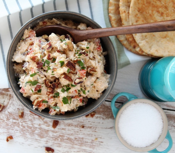grey bowl with chicken salad and spoon pita bread and salt and pepper in background