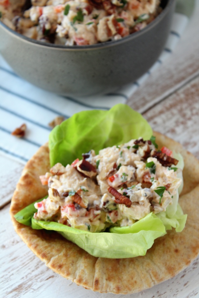 chicken salad in a lettuce cup on pita bread with bowl of chicken salad in background