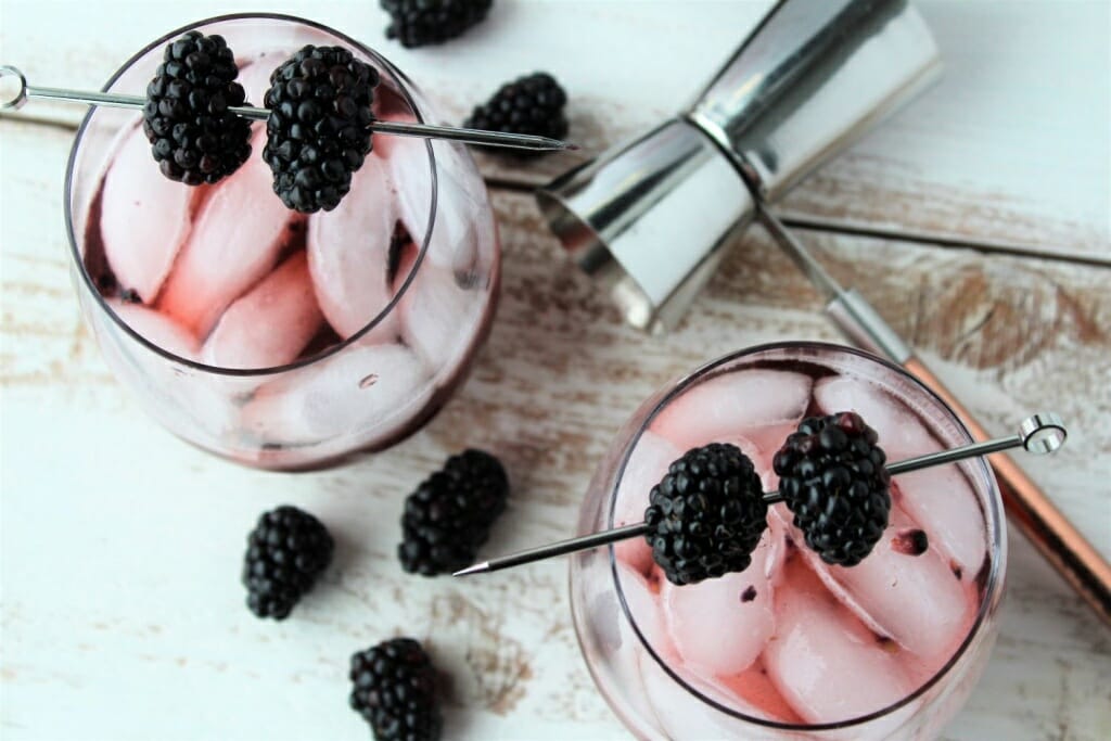 2 wine glasses filled with ice, mashed blackberries, sparkling wine, garnished with blackberries