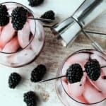 2 wine glasses filled with ice, mashed blackberries, sparkling wine, garnished with blackberries