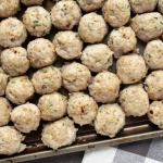 baking sheet pan with baked chicken meatballs laying on wood backdrop and towel.
