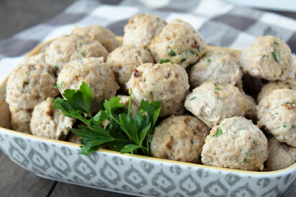 chicken meatballs in serving bowl on a wood backdrop